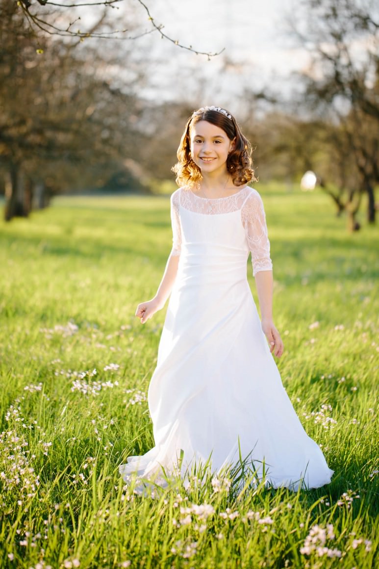 Entspannte Kommunionbilder in der Natur bei Philippsburg Kommunionkind weißes Kleid Obstwiese mit Blumen Frühlingswiese