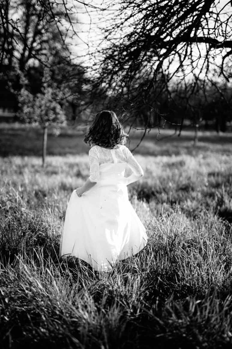 Entspannte Kommunionbilder in der Natur bei Philippsburg Kommunionkind weißes Kleid Obstwiese mit Blumen Frühlingswiese