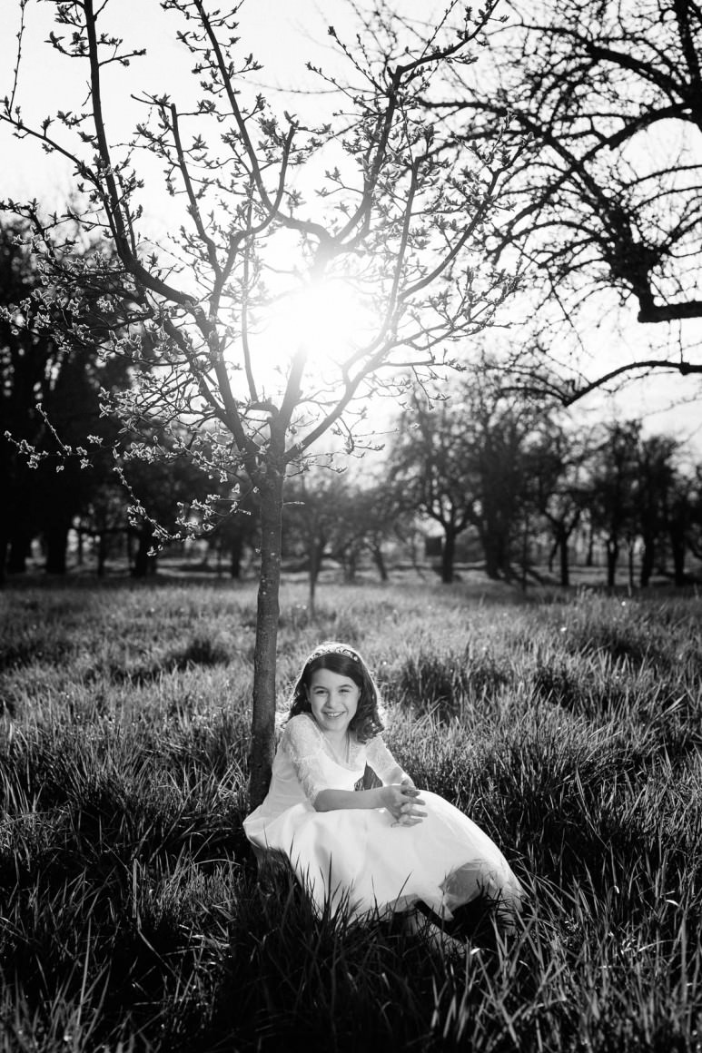 Entspannte Kommunionbilder in der Natur bei Philippsburg Kommunionkind weißes Kleid Obstwiese mit Blumen Frühlingswiese